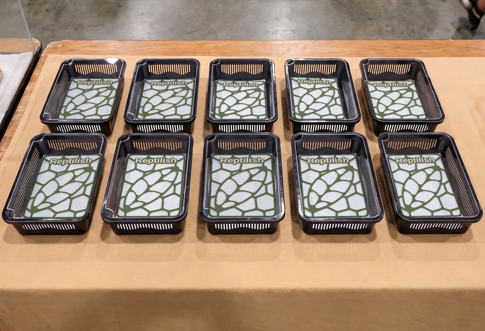 Ten black tubs in two rows on an expo display table, with Night Green Pebble Plates inside