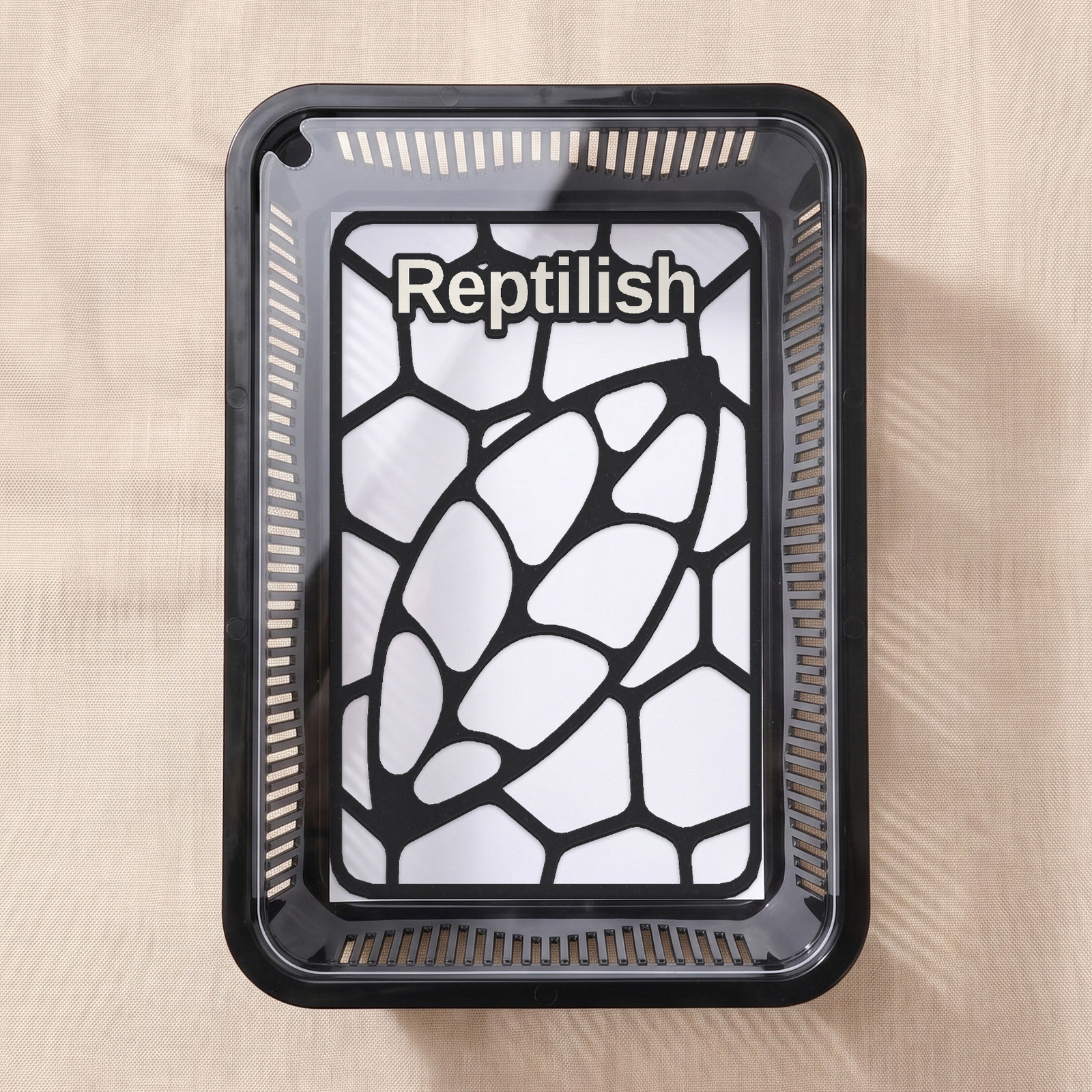 A black tub seen from above with a clear acrylic lid — a small opening notch at the top-left corner, a Carbon Black Pebble Plate inside
