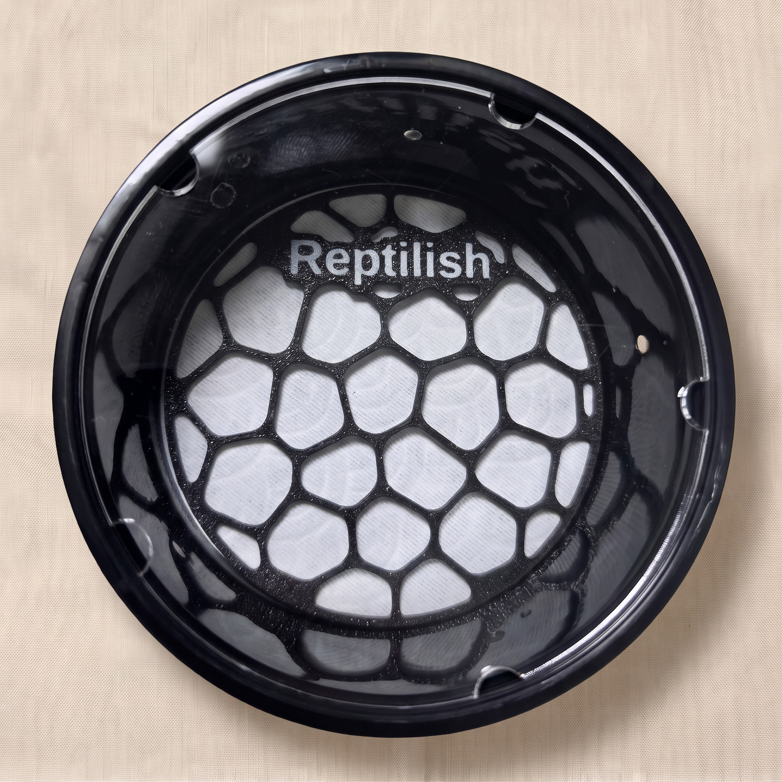 A deli cup with an acrylic lid seen from above, with a Carbon Black Pebble Plate inside