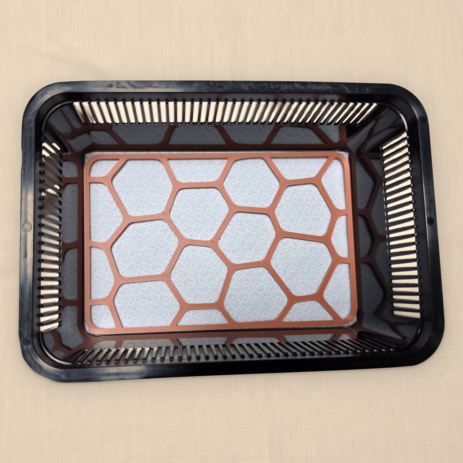 A rectangular Terracotta Pebble Plate without engraving, on the pad inside a small tub